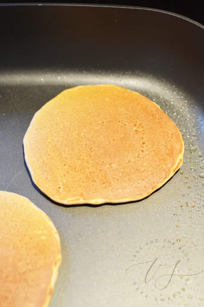 pancakes on a griddle bubbling and ready to turn over