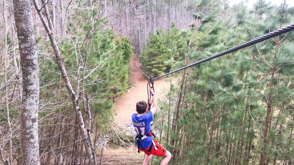teen boy zip lining from the tree tops