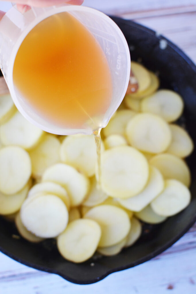 chicken stock and white potatoes in pan